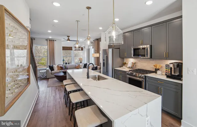 a kitchen with stainless steel appliances kitchen island granite countertop a stove a sink a refrigerator and a wooden floor