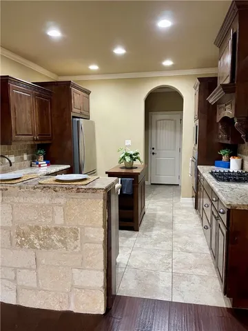 a kitchen with kitchen island granite countertop a sink stainless steel appliances and cabinets