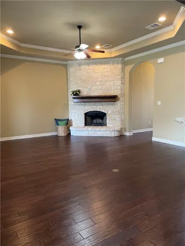 a view of an empty room with wooden floor and a fireplace