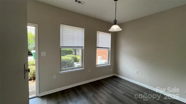 a view of an empty room with window and chandelier fan