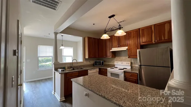 a kitchen with granite countertop stainless steel appliances a sink cabinets and a window