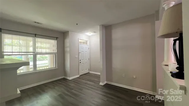 a view of an empty room with a window and wooden floor