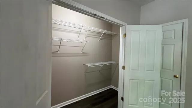 a walk in closet with wooden floor