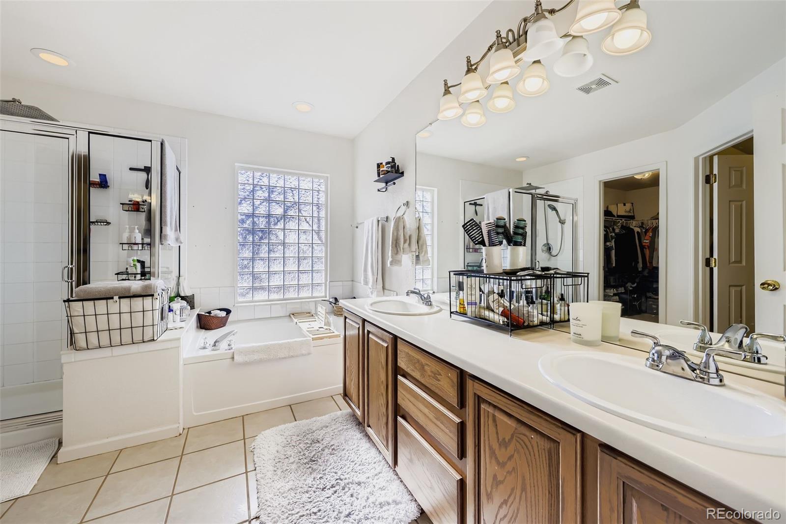 11668 Xavier Way Westminster, CO 80031 - Photo 13 of 22 a spacious bathroom with a sink a large mirror and a bathtub