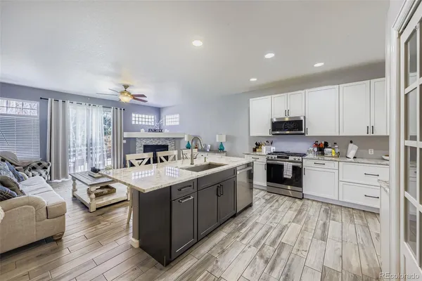 a open kitchen with stainless steel appliances granite countertop a stove oven and a refrigerator with wooden floor