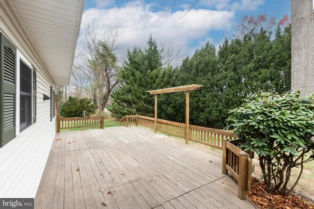 a white house that has a small yard and couches chairs with wooden fence