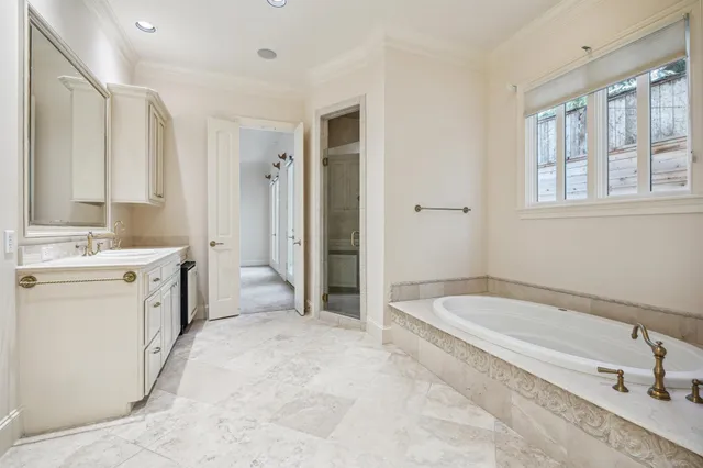 a large white bathroom with a large mirror vanity and a bathtub