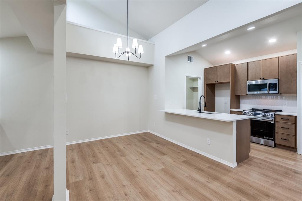 17490 Meandering Way, Unit 2202 Dallas, TX 75252 - Photo 11 of 24 Open-concept room featuring wood-finish flooring, vaulted ceilings, and a modern chandelier