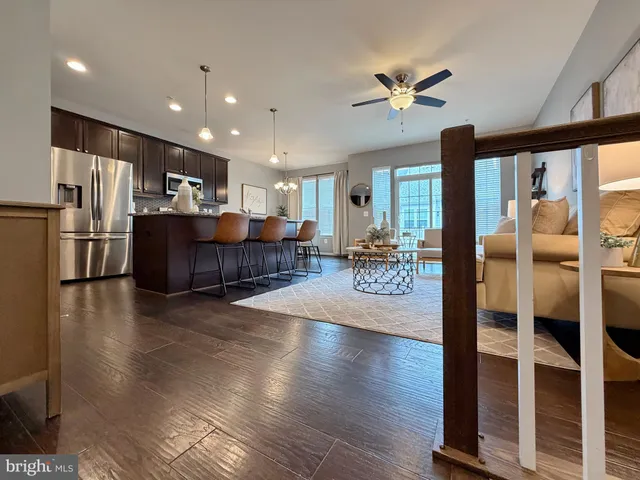 a kitchen with stainless steel appliances granite countertop a sink a stove a refrigerator a microwave oven with white cabinets and wooden floor