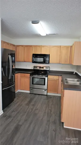a kitchen with granite countertop a refrigerator and a stove top oven