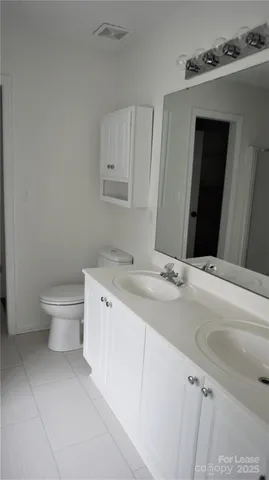 a bathroom with a granite countertop sink and a toilet