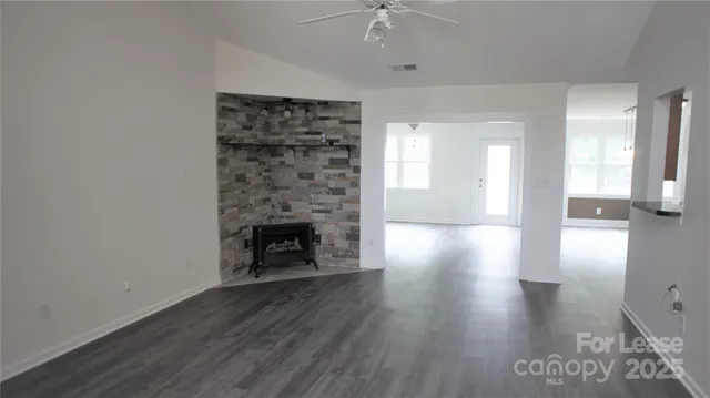 a view of a livingroom with wooden floor a fireplace and windows