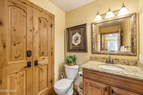 a bathroom with a granite countertop sink a toilet and a mirror