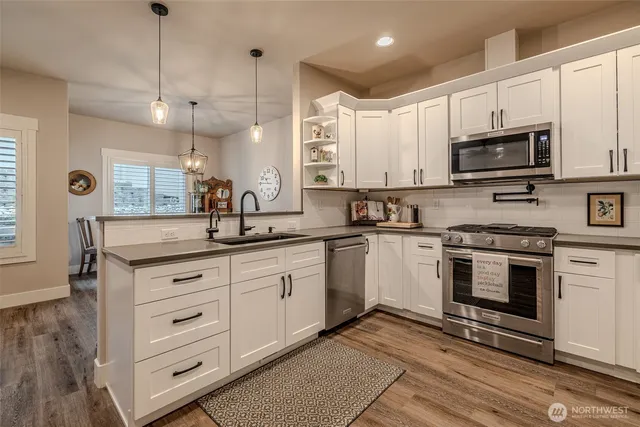 a kitchen with stainless steel appliances granite countertop a stove a sink and a microwave