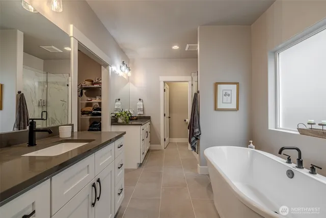 a spacious bathroom with a double vanity sink a mirror and a bathtub