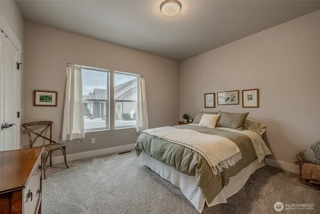 a bedroom with a bed a table and chair with a large window