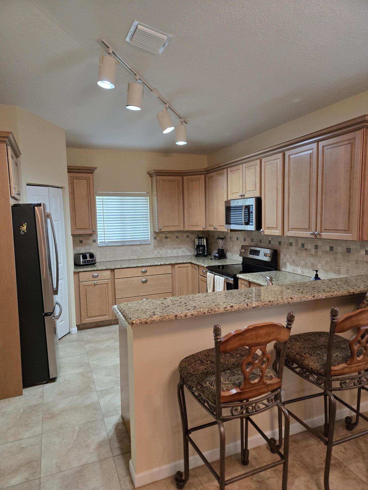 2297 Windjammer Way West Palm Beach, FL 33411 - Photo 20 of 56 a kitchen with granite countertop wooden cabinets a sink a stove a refrigerator and island