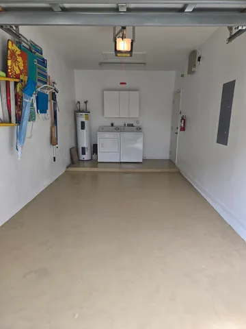 a backyard of a house with table and chairs under a large tree