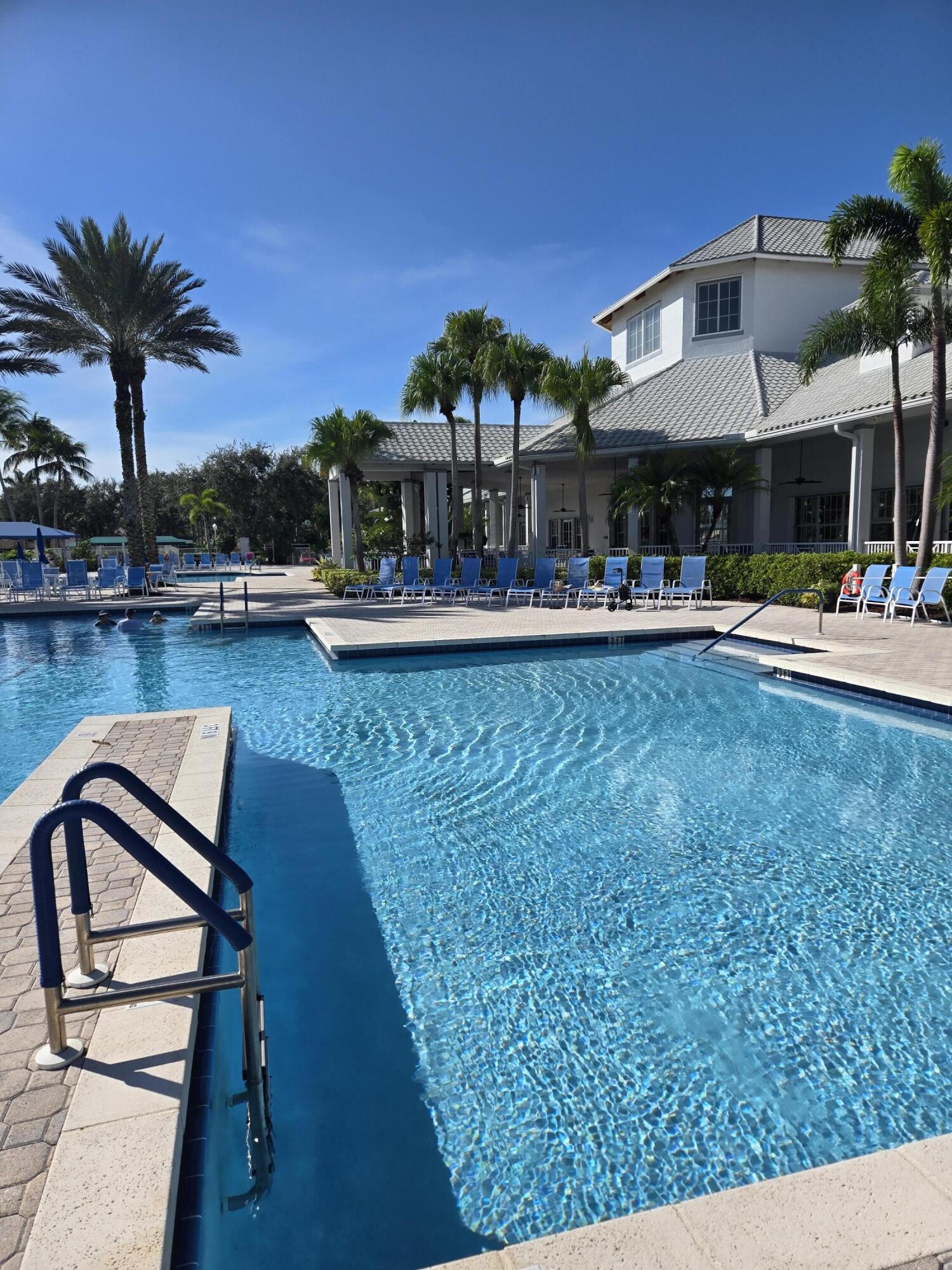 2297 Windjammer Way West Palm Beach, FL 33411 - Photo 46 of 56 a view of a swimming pool with a table and chairs under an umbrella