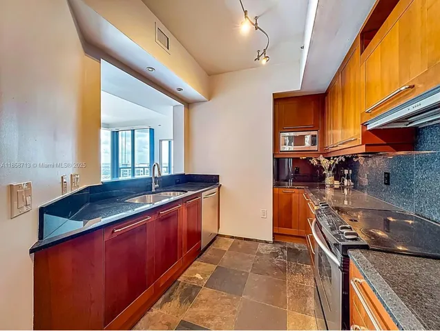 a kitchen with stainless steel appliances granite countertop a sink and a stove