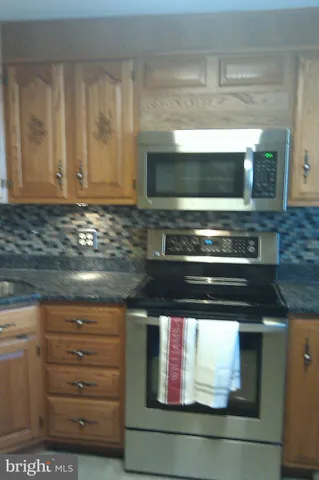 a kitchen with granite countertop a stove and a microwave