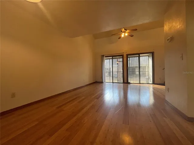 a view of empty room with wooden floor and fan