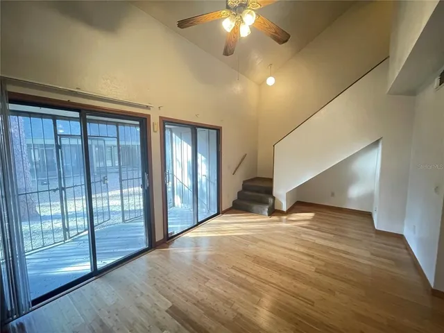 a view of an empty room with glass door and wooden floor