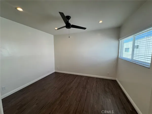 an empty room with wooden floor fan and windows