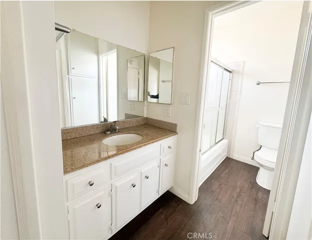 a bathroom with a granite countertop sink toilet and mirror