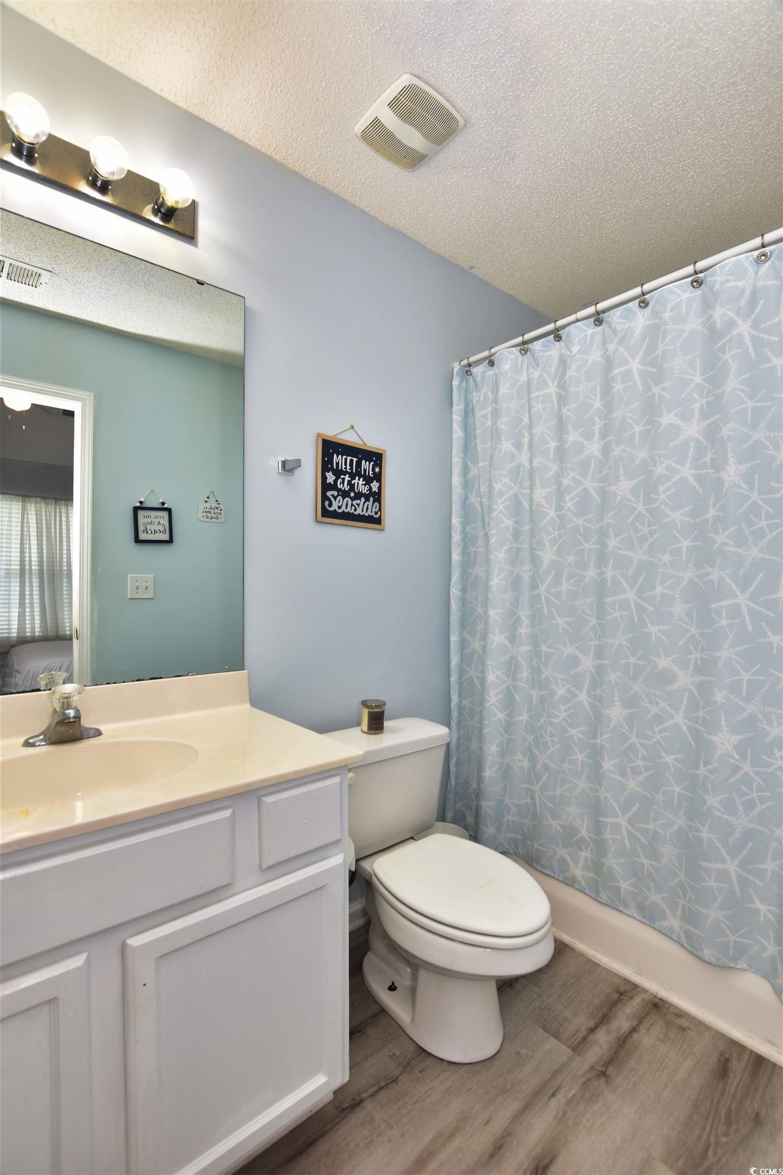 1065 Pinwheel Loop, Unit 1065 Myrtle Beach, SC 29577 - Photo 12 of 27 Bathroom featuring vanity, toilet, wood-type flooring, and a textured ceiling