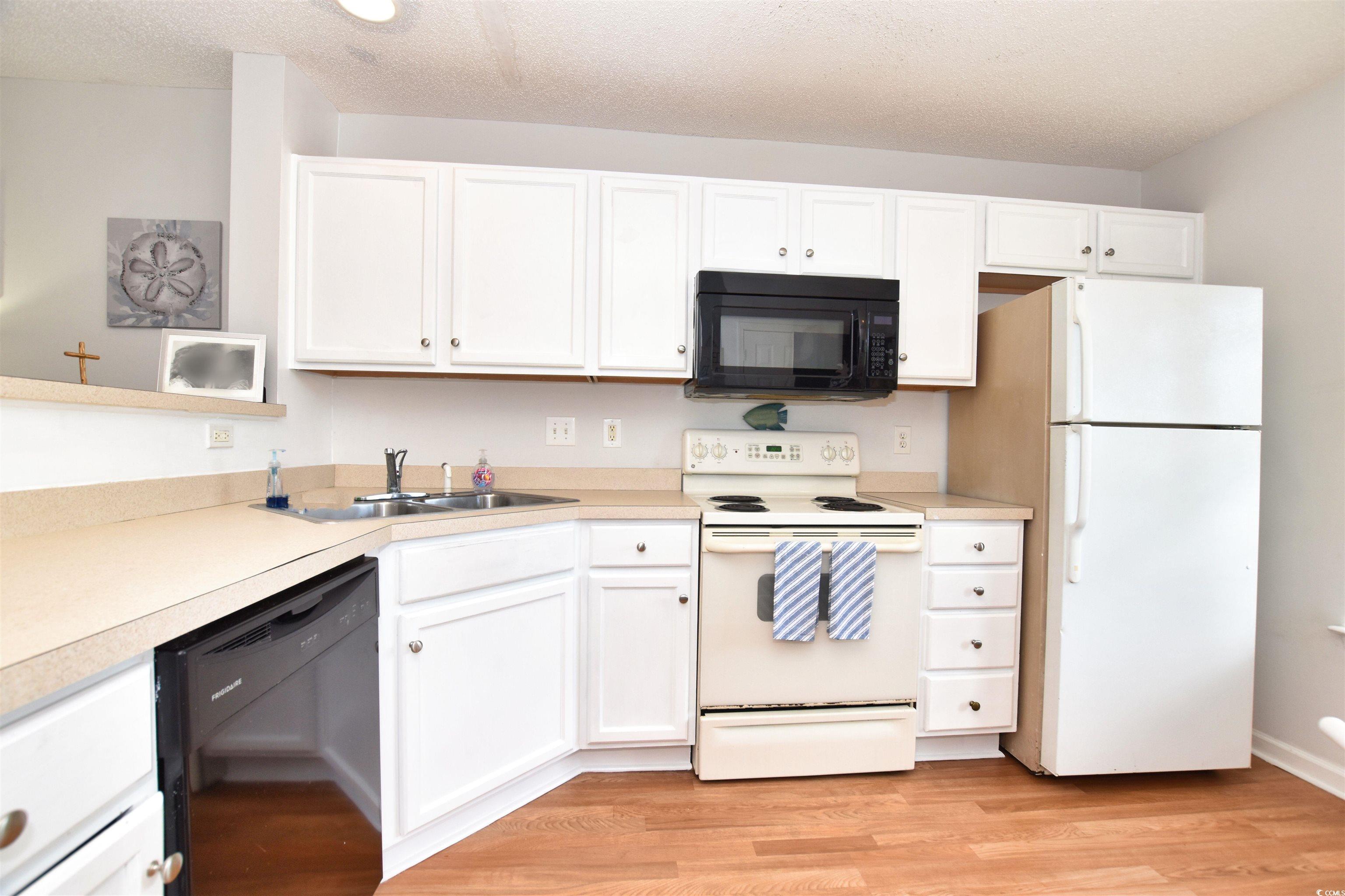 1065 Pinwheel Loop, Unit 1065 Myrtle Beach, SC 29577 - Photo 5 of 27 Kitchen with light wood-type flooring, black appliances, and white cabinets