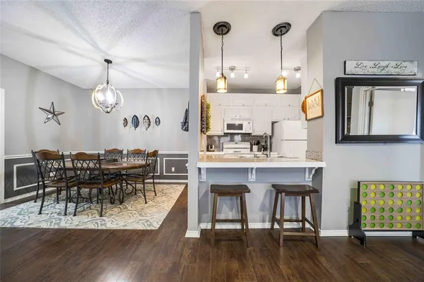 a dining room with wooden floor a chandelier a wooden table and chairs