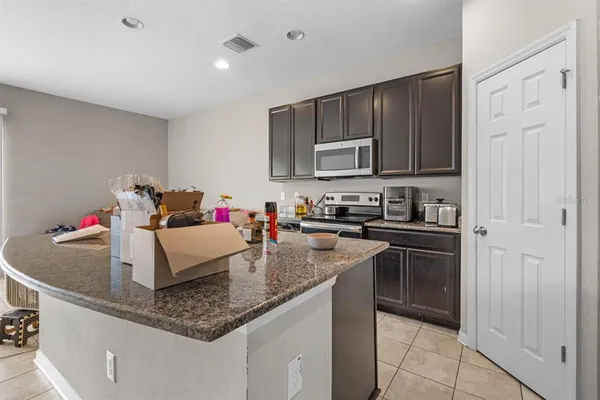 a kitchen with kitchen island granite countertop a sink dishwasher stove and cabinets