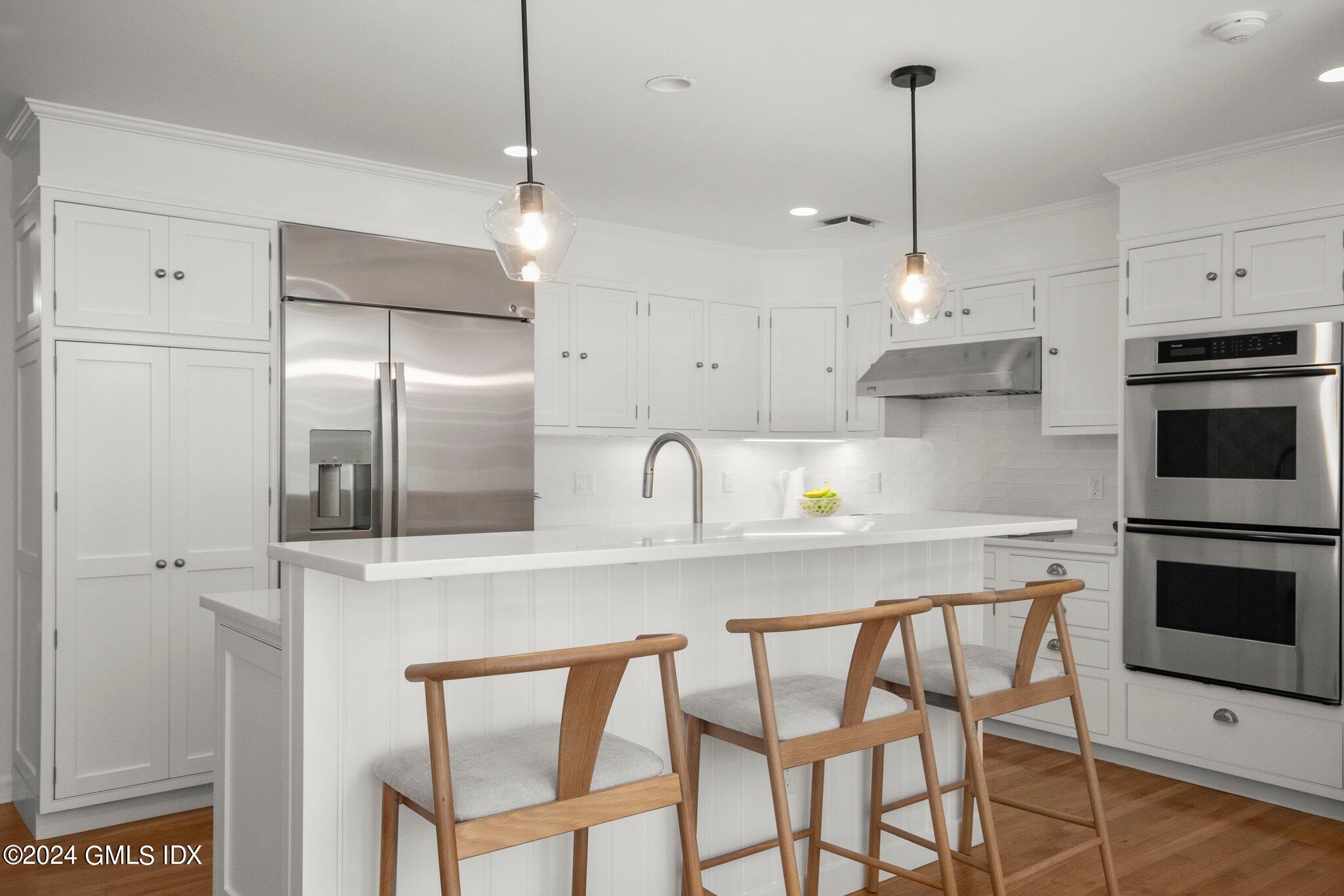 40 Eureka Terrace Stamford, CT 06902 - Photo 6 of 28 a kitchen with stainless steel appliances granite countertop a sink a stove a refrigerator and island with wooden floor
