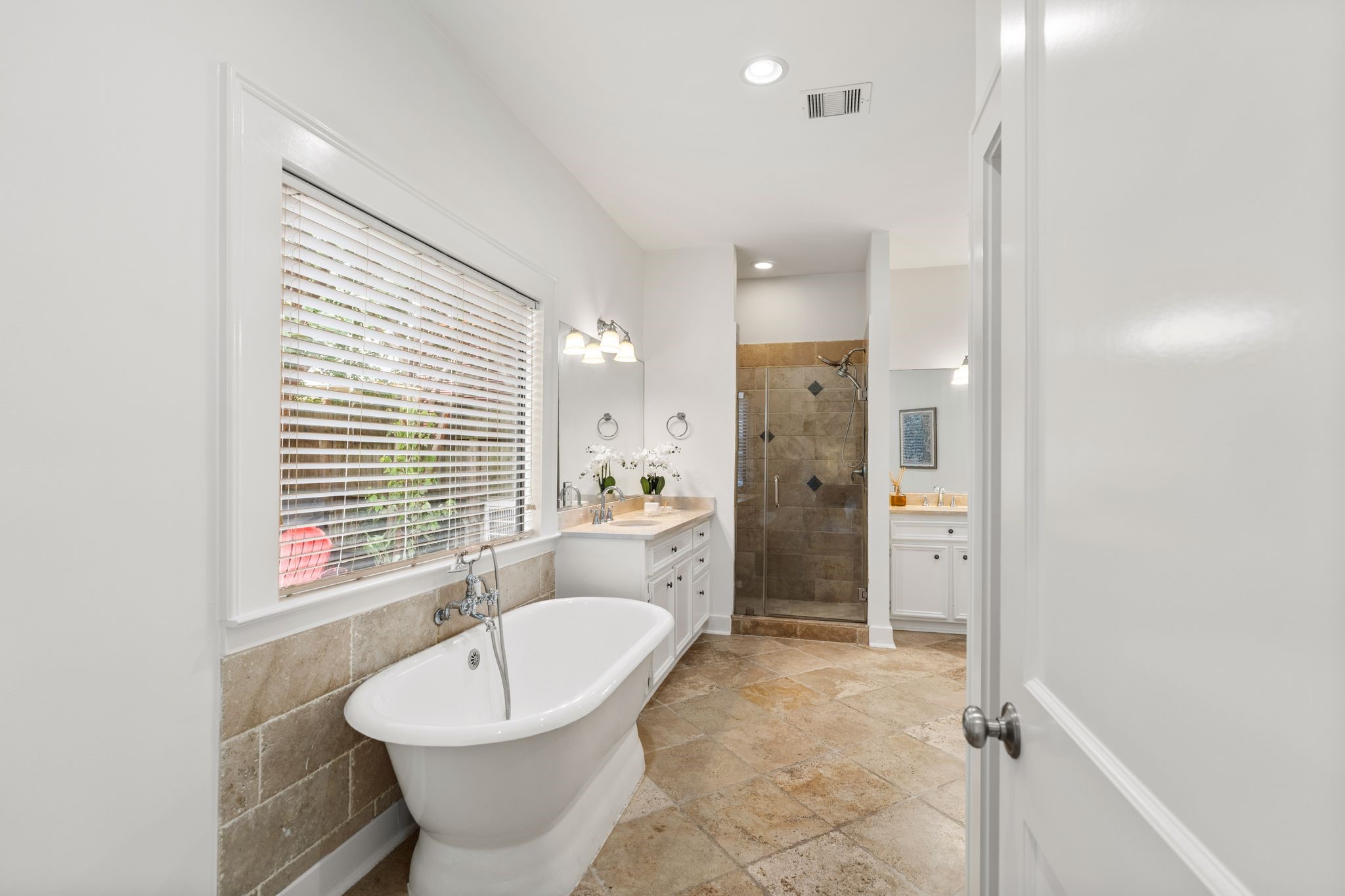 307 East 8th Street Houston, TX 77007 - Photo 17 of 35 Relax and unwind in the luxurious freestanding soaking tub, beautifully framed by a tiled surround and a large picture window that fills the space with natural light. The separate glass-enclosed walk-in shower completes the spa-like retreat, offering the perfect combination of elegance and everyday convenience.