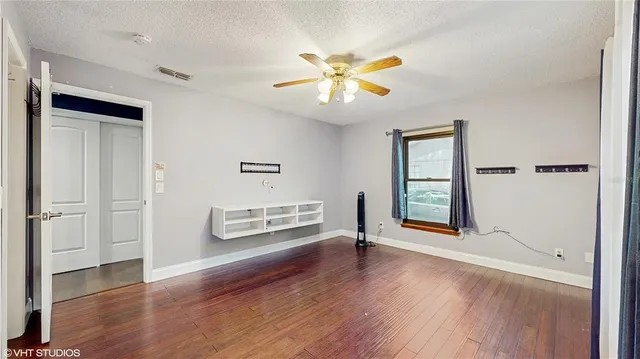 a view of an empty room with window and wooden floor