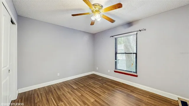 an empty room with windows and fan