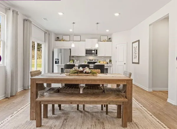 a living room with stainless steel appliances furniture dining table and wooden floor