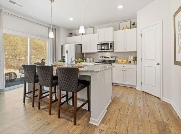 a kitchen with stainless steel appliances stove refrigerator dining table and chairs