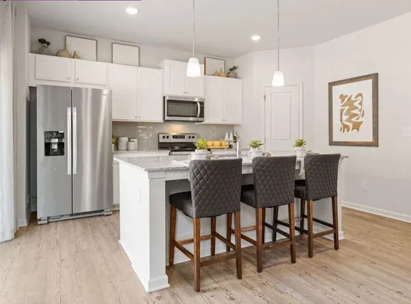 a kitchen with stainless steel appliances a dining table chairs refrigerator and microwave