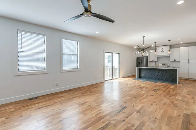 a view of empty room with kitchen and window