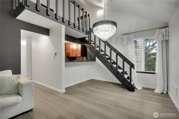 a view of a hallway with wooden floor stairs and a chandelier