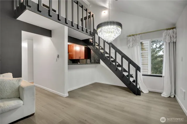 a view of a hallway with wooden floor stairs and a chandelier