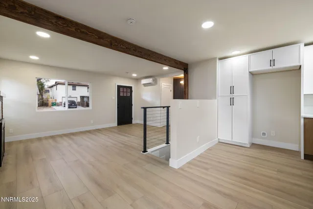 a view of a livingroom with wooden floor and white cabinets