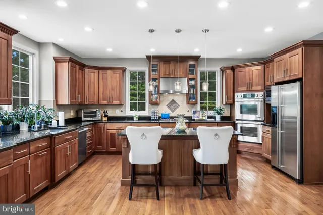 a kitchen with stainless steel appliances granite countertop a dining table chairs refrigerator sink and cabinets