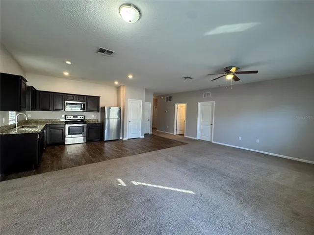 a large kitchen with stainless steel appliances kitchen island granite countertop a stove refrigerator and a microwave