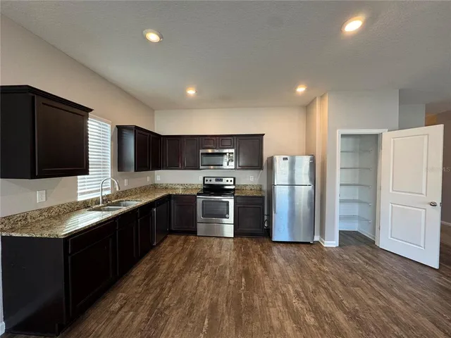 a kitchen with stainless steel appliances granite countertop a refrigerator a stove a sink dishwasher and a refrigerator