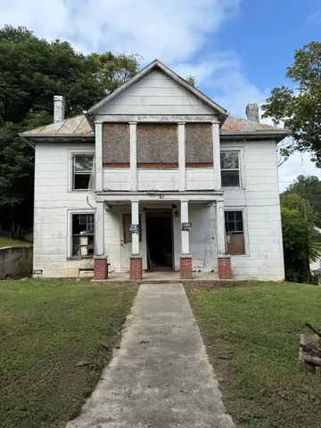a front view of a house with a yard and trees