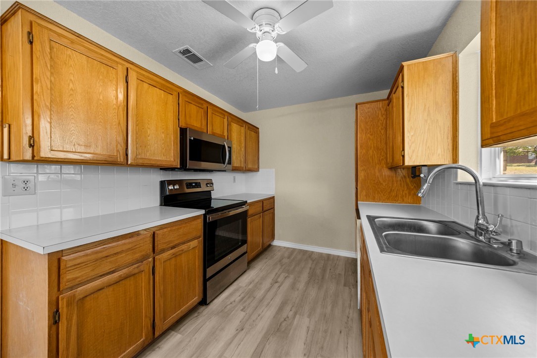 1012 Cherokee Trail Kempner, TX 76539 - Photo 18 of 27 a kitchen with stainless steel appliances granite countertop a sink a stove top oven a chimney with wooden floor and cabinets