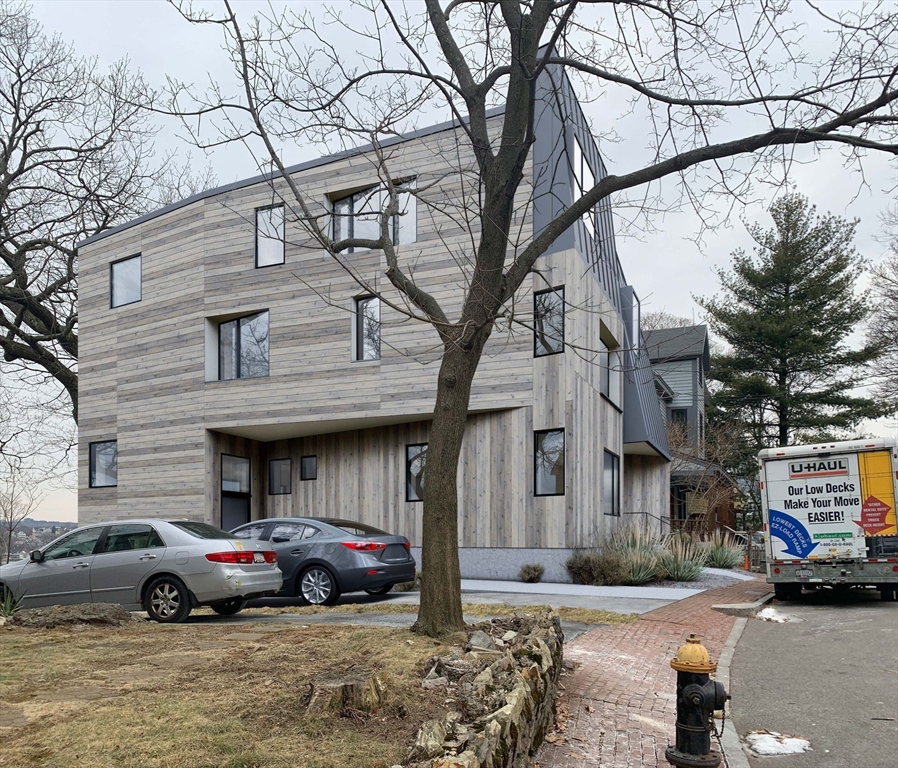 63 Beech Glen Street Boston, MA 02119 - Photo 3 of 9 a front view of a building with parking space and a parked car